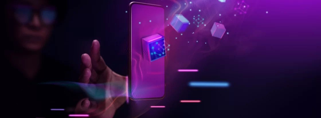 Slika prikazuje futuristični prizor z lebdečim pametnim telefonom iz katerega izstopajo svetleči digitalni kubusi obkroženi z vijoličnimi in modrimi svetlobnimi učinki kar simbolizira tehnologijo veriženja blokov digitalna sredstva ali metaverse platformo