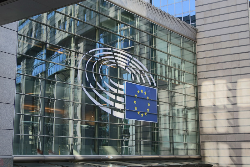 Zunanjost stavbe z veliko stekleno fasado prikazuje logotip Evropskega parlamenta z evropsko zastavo v središču