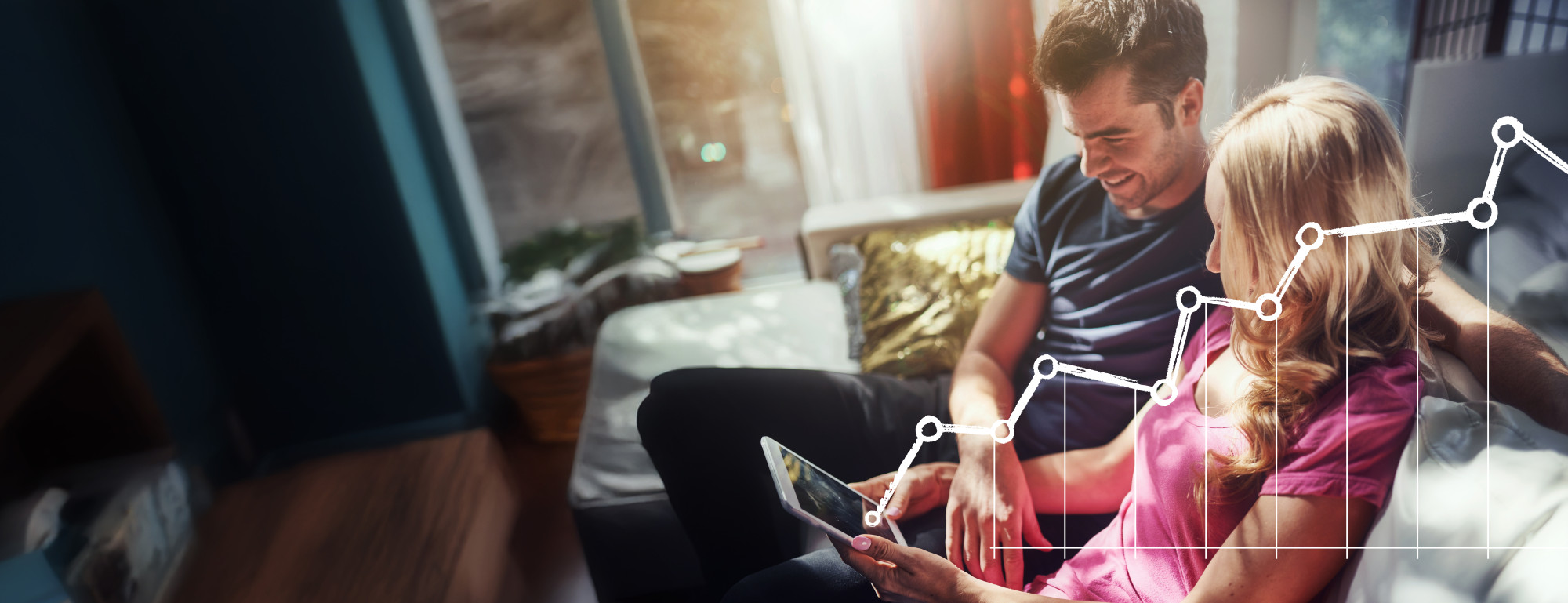 Moški in ženska sedita na kavču s tablico v roki iz katere gre graf rasti