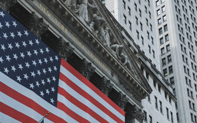 Velika ameriška zastava visi pred vhodom v newyorško borzo obdano z visokimi poslovnimi stavbami