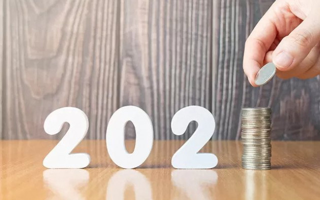 Roka dodaja kovanec na kupček ki predstavlja številko ena in skupaj z belimi številkami tvori letnico 2021 kar simbolizira finančne cilje ali varčevanje v novem letu