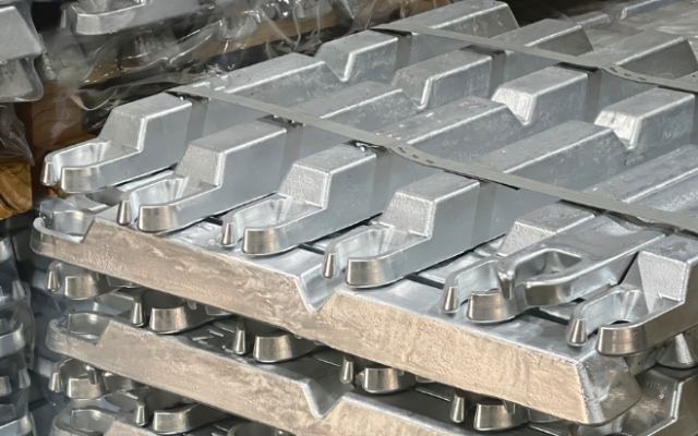 Na sliki so zloženi sijoči aluminijasti ingoti pripravljeni za industrijsko uporabo.