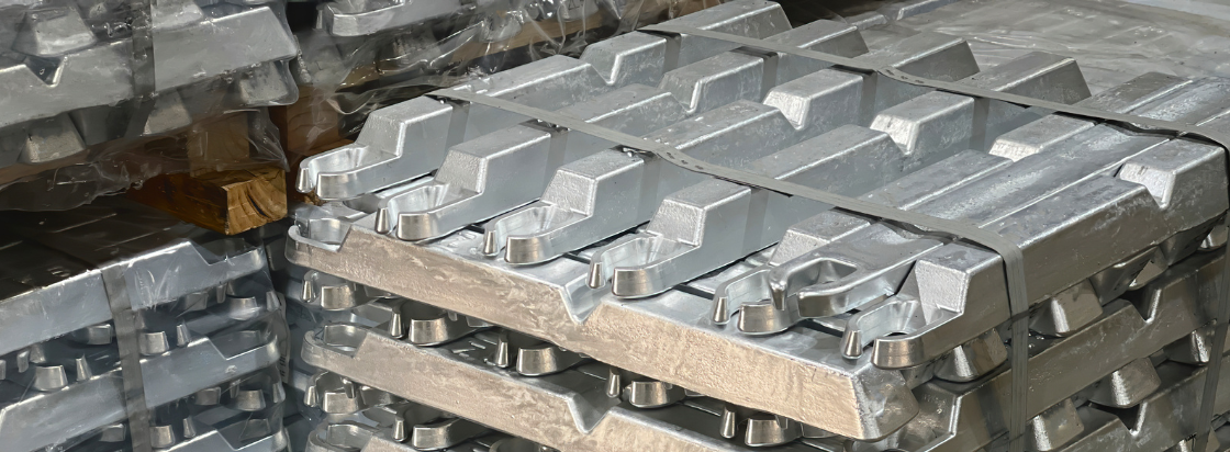 Na sliki so zloženi sijoči aluminijasti ingoti pripravljeni za industrijsko uporabo.