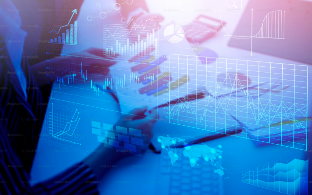 Oseba sedi za mizo z grafi in dokumenti medtem ko digitalni prikazi podatkov in statistike lebde nad prizorom