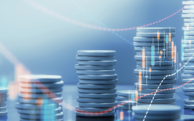 Na sliki so kupčki kovancev z digitalnimi grafikoni kar simbolizira finančno rast in vlaganja