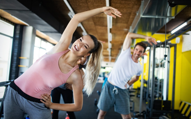 moški in ženska med raztegovanjem v fitnesu