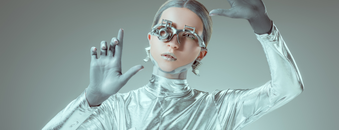 Robot v srebrnem futurističnem videzu z visokotehnološkimi očali in dvignjenimi rokami deluje kot inteligentno bitje iz prihodnosti.