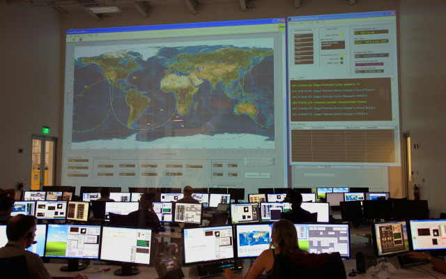 Nadzorni center z velikim zaslonom svetovnega zemljevida in več računalniškimi postajami