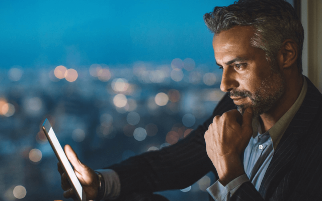 moški ponoci gleda na tablico na balkonu