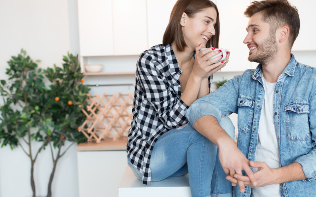 Slika moškega in ženske v domači kuhinji, ki gledata drug proti drugemu.