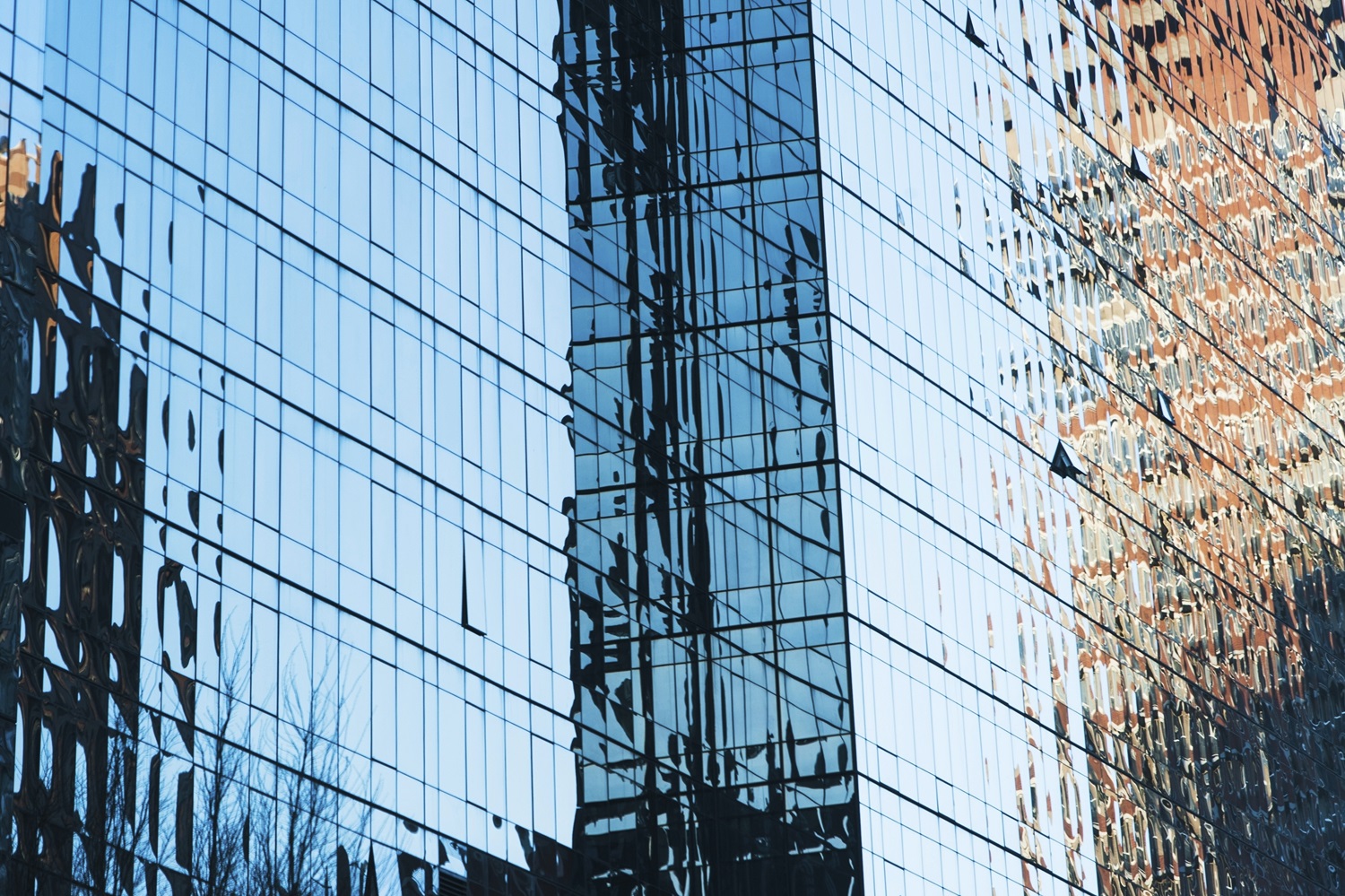 Odsev mestnih stavb na stekleni fasadi sodobne poslovne zgradbe