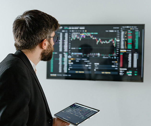 Finančni strokovnjak gleda na zaslon na steni, ki prikazuje gibanje vrednosti delnic