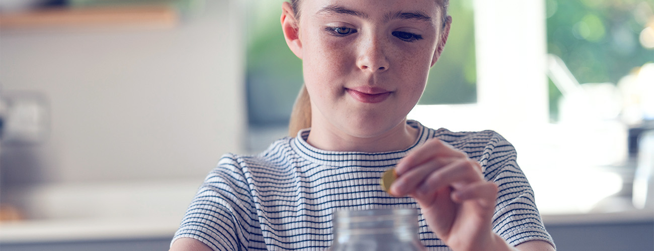 Deklica meče kovanec v steklen kozarec