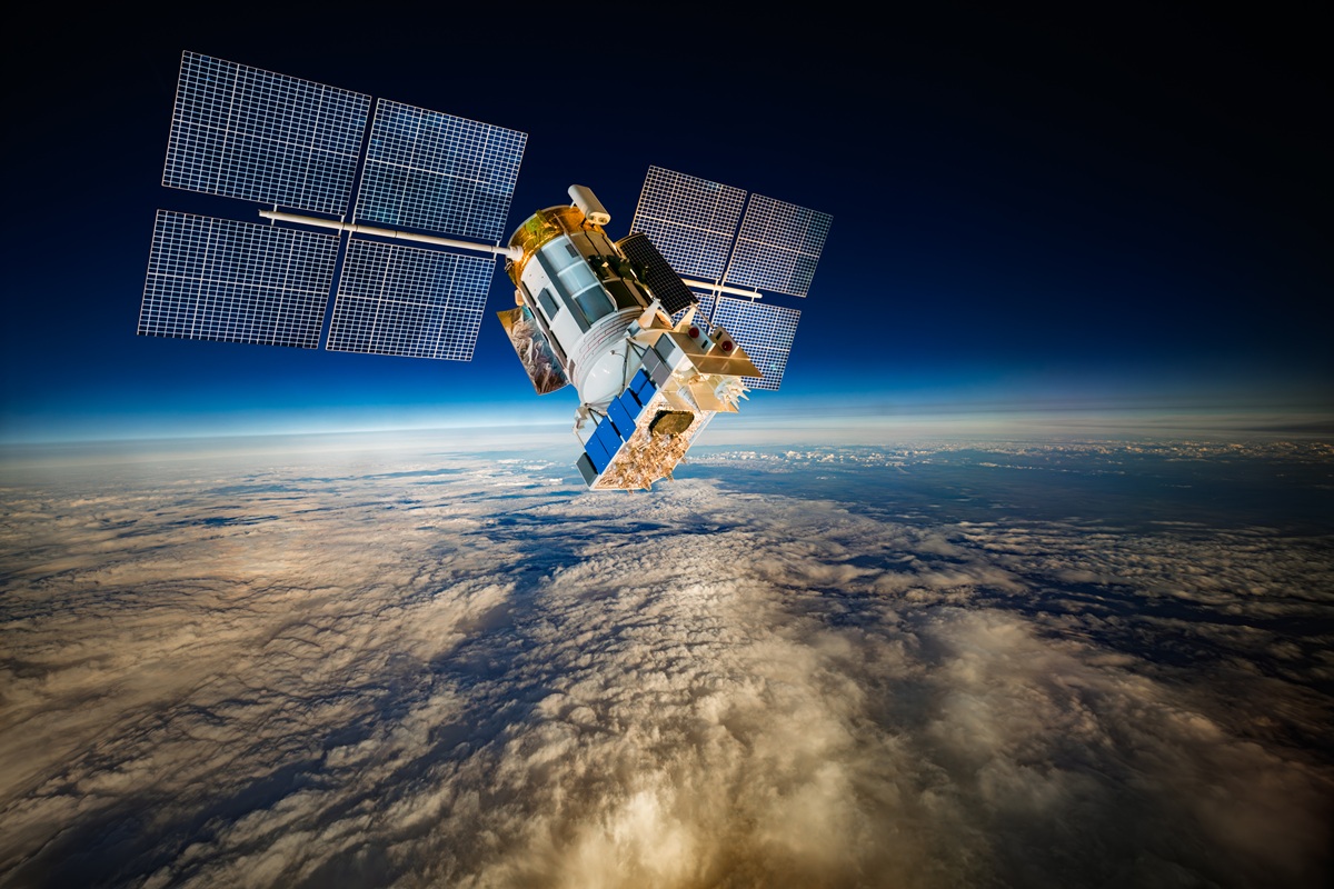 Satelit s sončnimi paneli kroži nad Zemljo in ponazarja razvoj vesoljske tehnologije ter podatkovnih centrov v orbiti