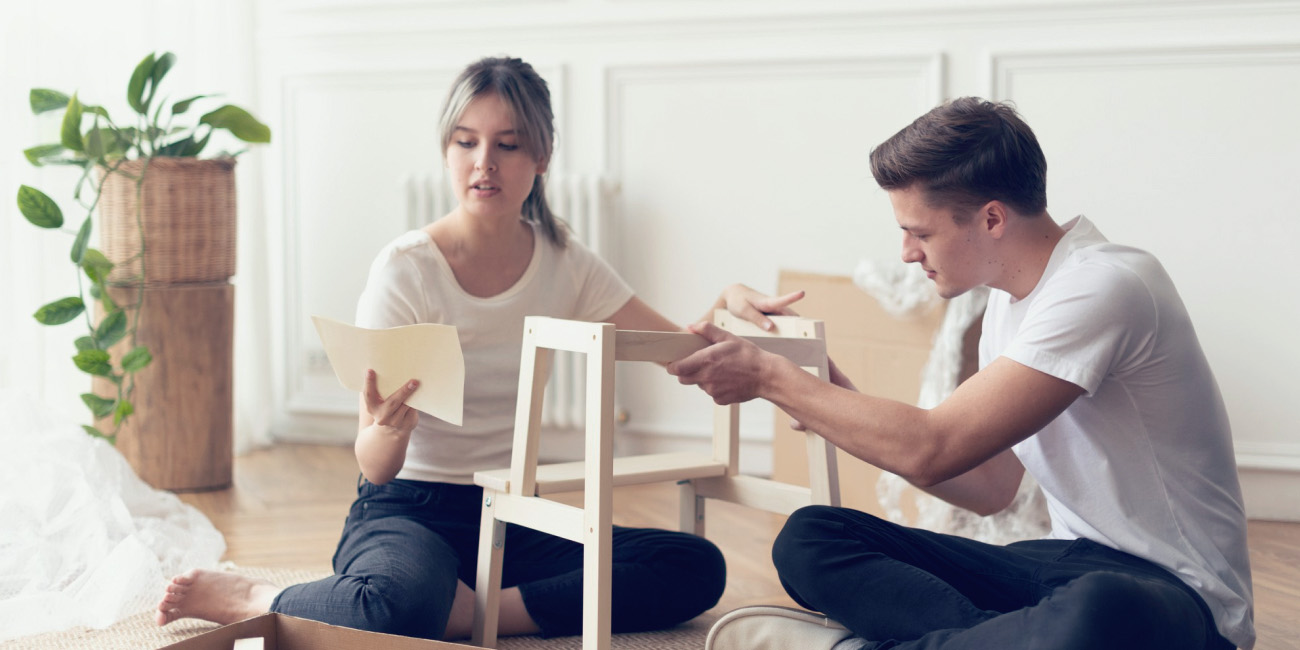 Moški in ženska na tleh dnevne sobe sestavljata pohištvo