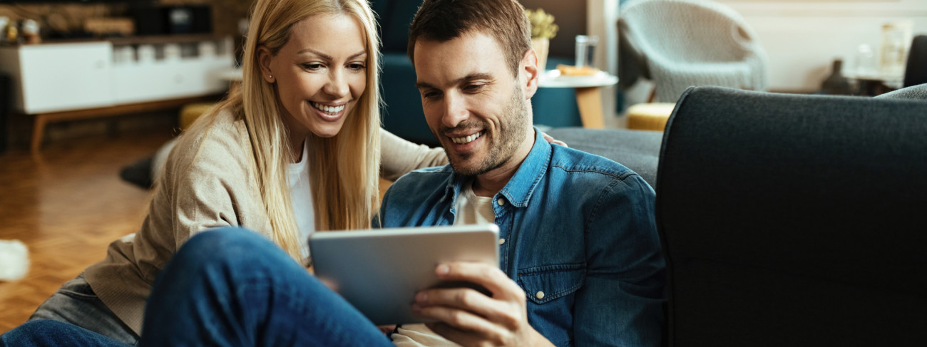 Nasmejan par sproščeno sedi doma in skupaj gleda vsebino na tablici