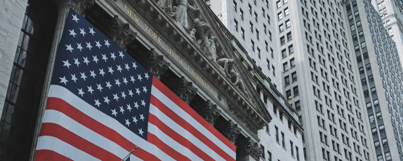 Velika ameriška zastava visi pred vhodom v newyorško borzo obdano z visokimi poslovnimi stavbami