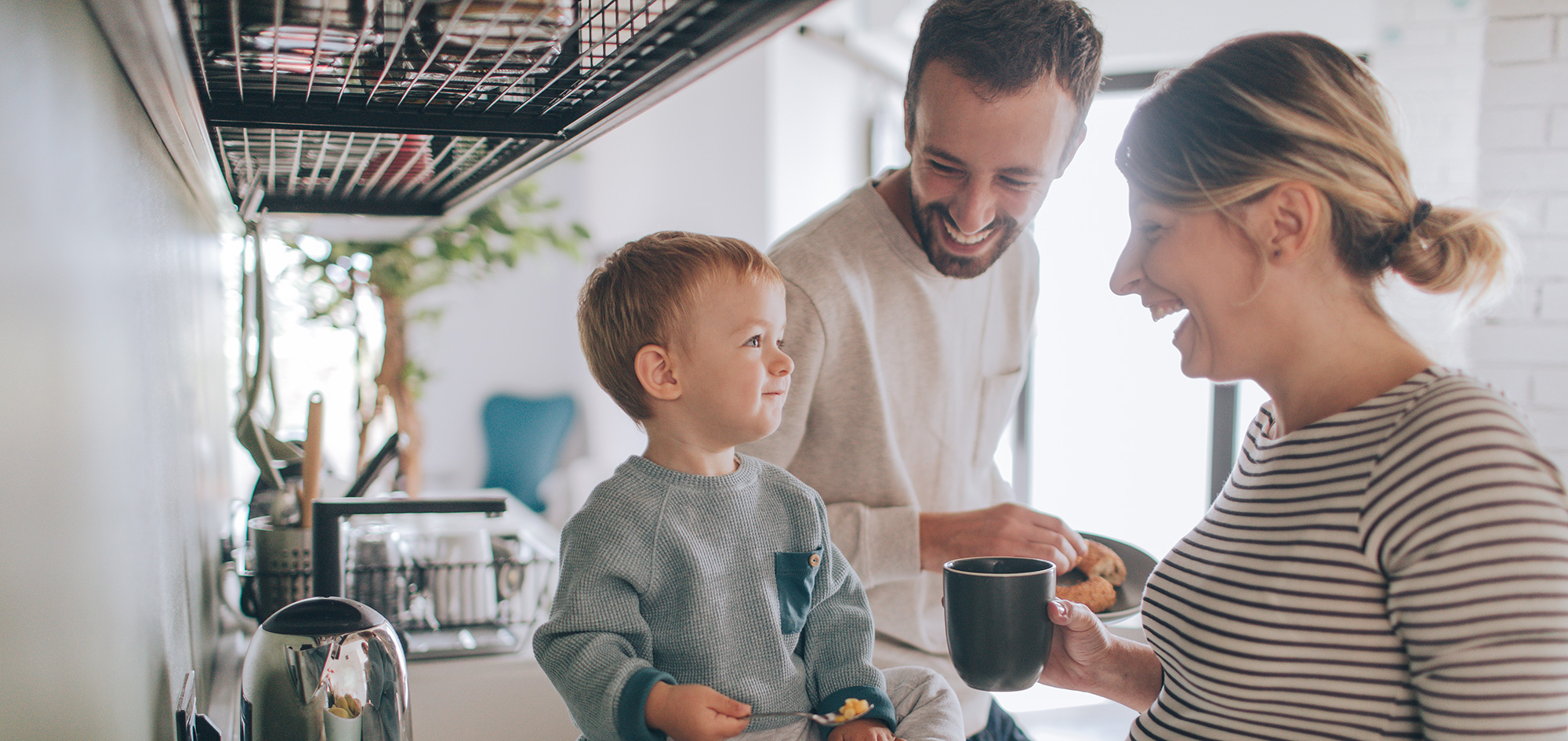 Srečna družina v kuhinji skupaj zajtrkuje in se smehlja med sproščenim pogovorom