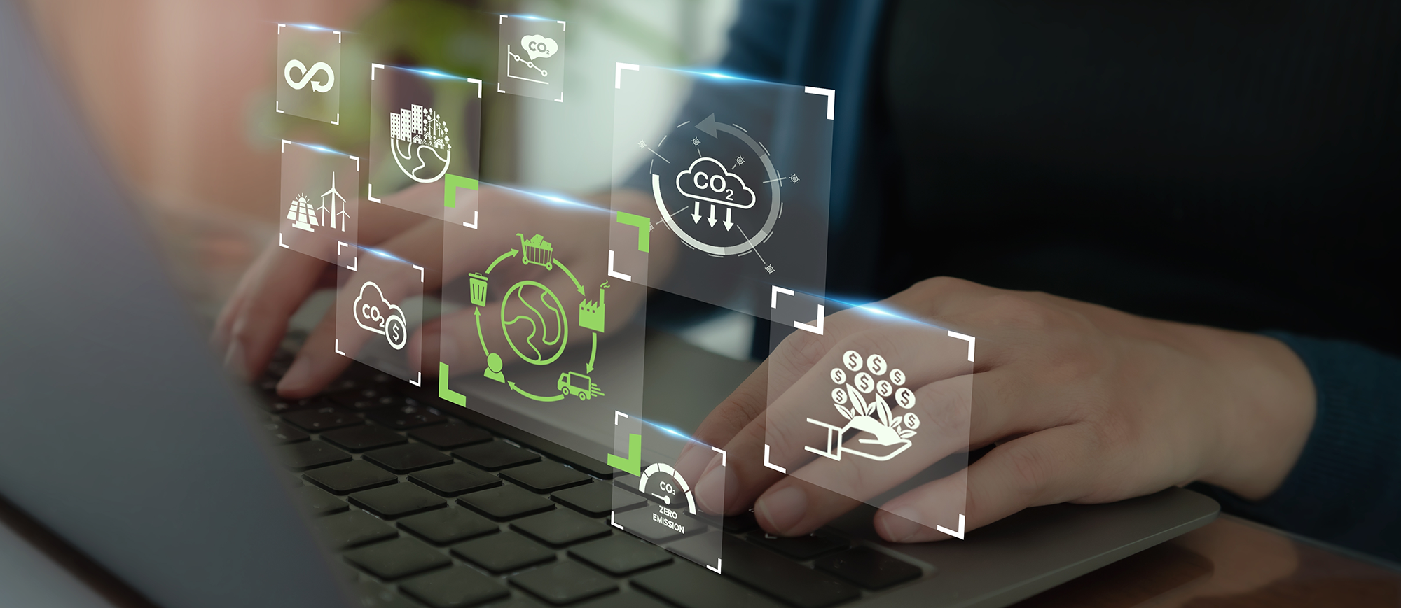 Oseba tipka na prenosniku obkrožena z lebdečimi ikonami trajnostnega razvoja in zmanjševanja emisij CO2