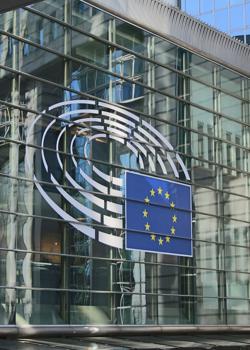 Zunanjost stavbe z veliko stekleno fasado prikazuje logotip Evropskega parlamenta z evropsko zastavo v središču