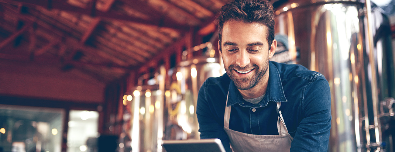 Slika moškega v delavnici, ki gleda v mobilni telefon