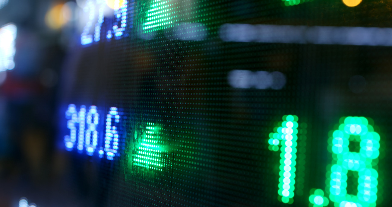 Svetleče zelene digitalne številke in puščice na borznem prikazovalniku prikazujejo podatke o trgovanju z vrednostnimi papirji