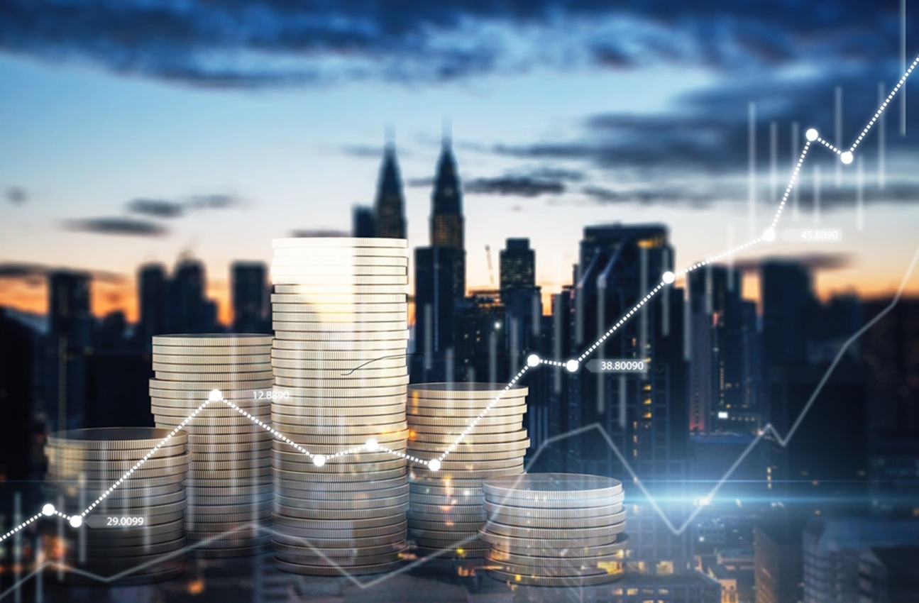 Kupčki kovancev pred mestno panoramo z digitalnim prikazom rasti finančnih grafov.