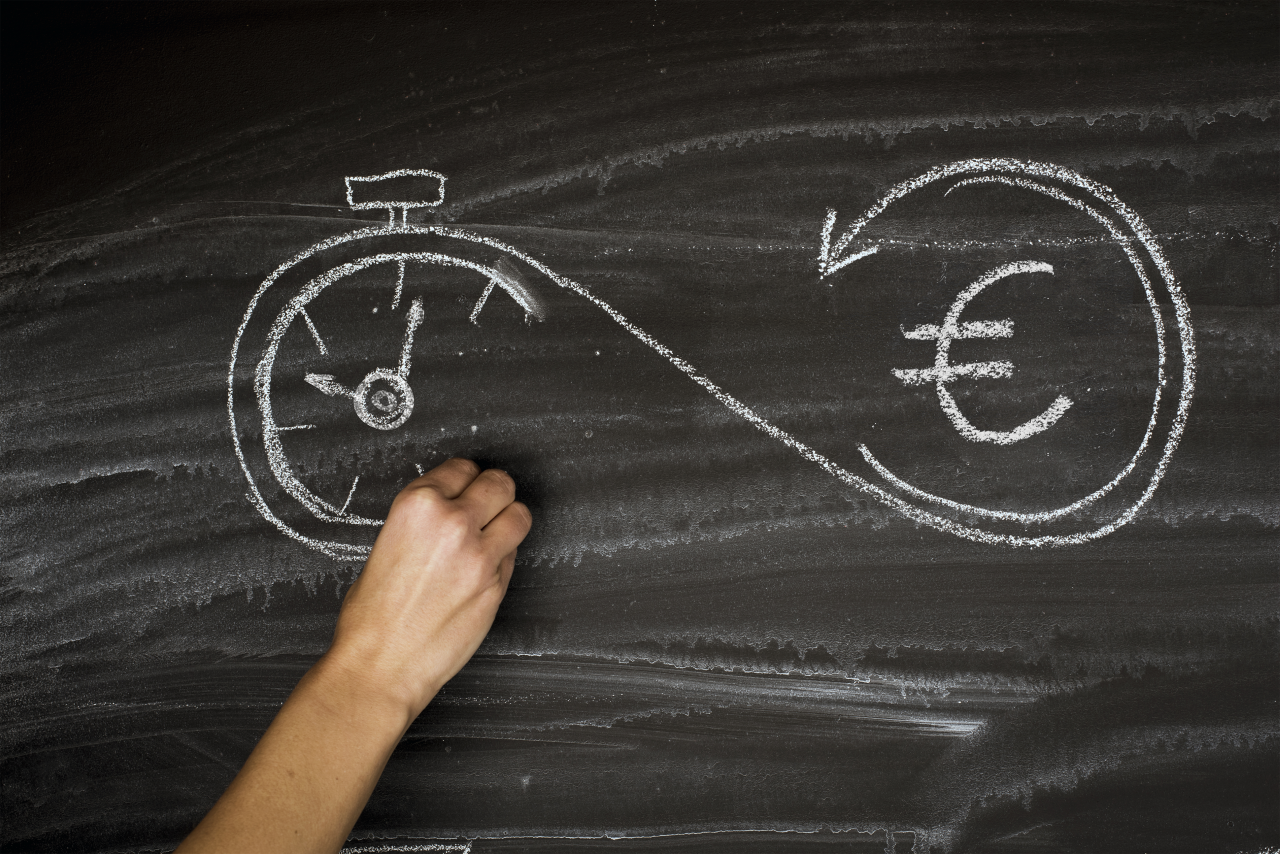 Roka riše s kredo na tablo simbol neskončnosti ki povezuje štoparico in evro znak kar ponazarja povezavo med časom in denarjem