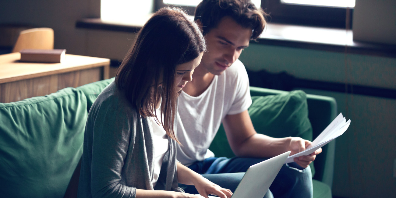 Mlad par sedi na kavču in gleda v finančne dokumente