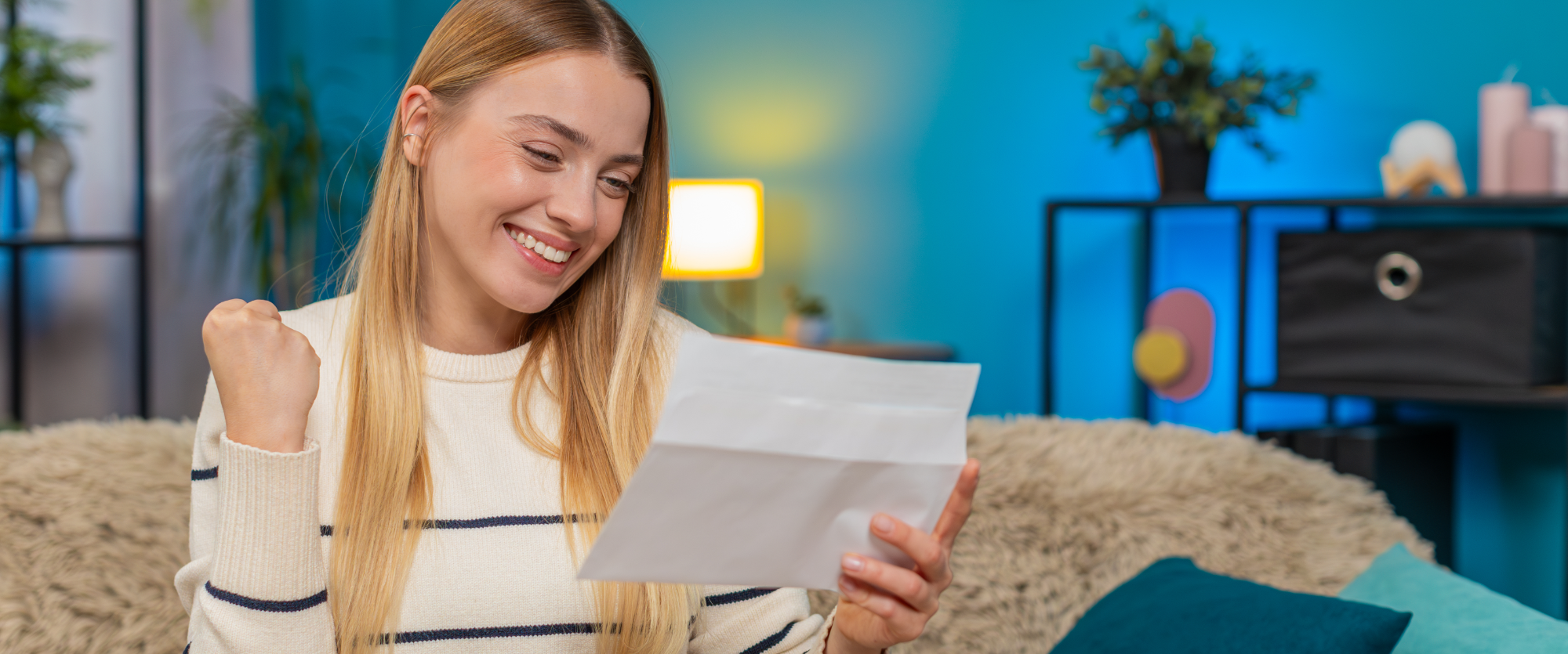 Zadovoljna ženska sedi na kavču in gleda v dokument, ki ga je prejela po pošti.