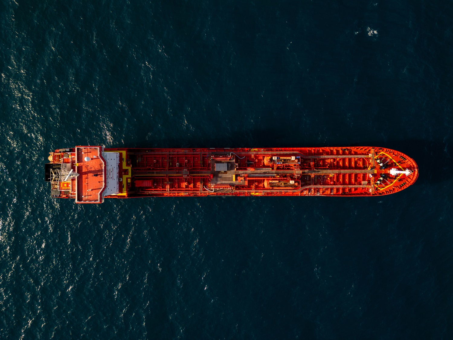 Pogled iz zraka na velik rdeč naftni tanker, ki pluje po odprtem morju