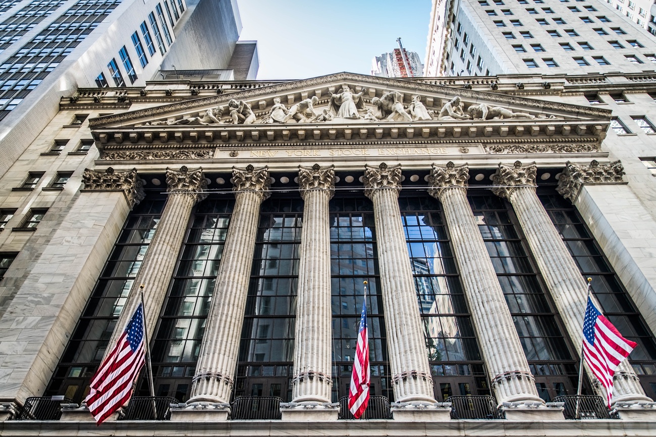 Pročelje newyorške borze (NYSE) z mogočnimi stebri in ameriškimi zastavami