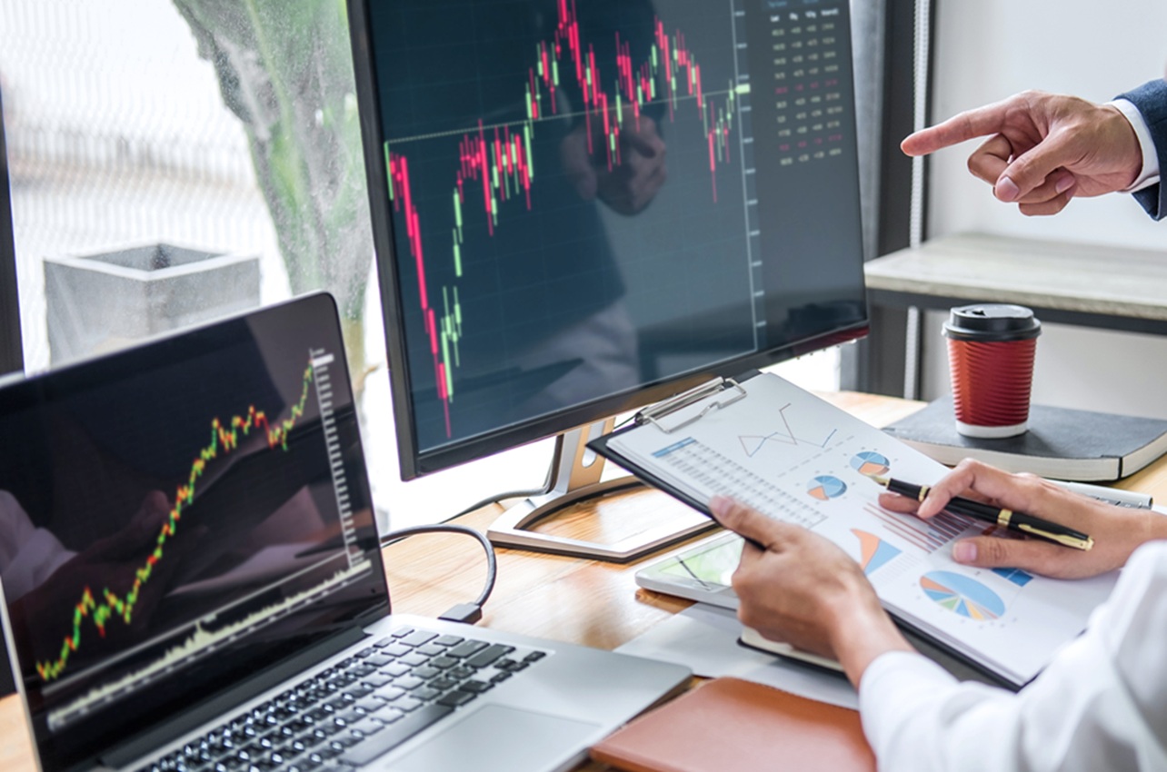 Analiza finančnih grafov na zaslonu računalnika z dokumenti in prikazom podatkov na mizi