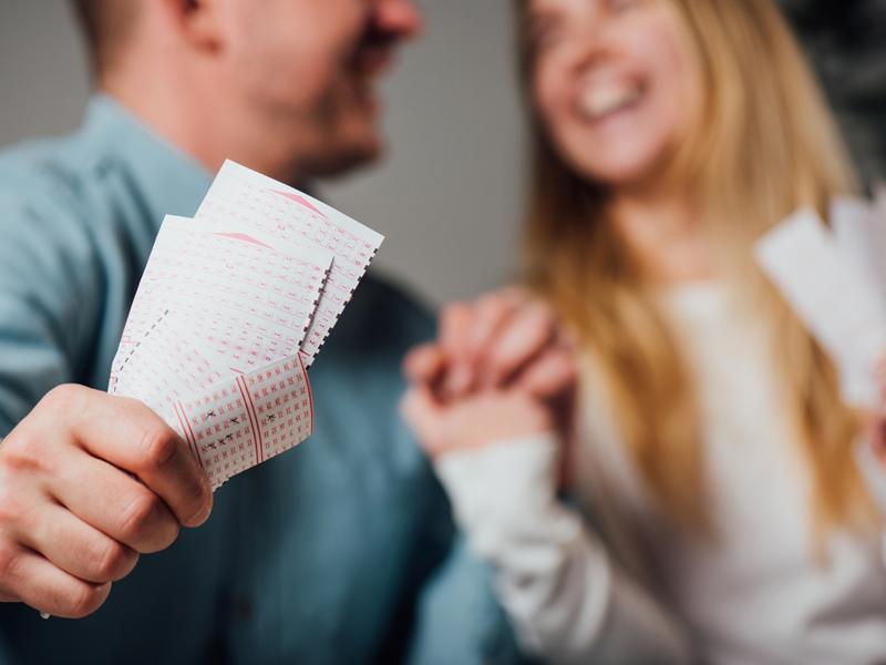 Nasmejan par z loterijskimi srečkami v rokah
